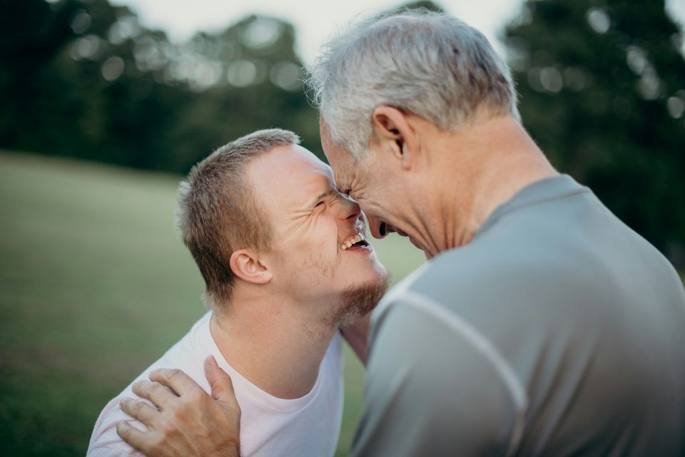 A young man with Down’s syndrome and his father sharing a happy moment