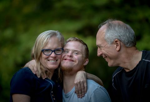 A family with their adult son, smiling together outdoors
