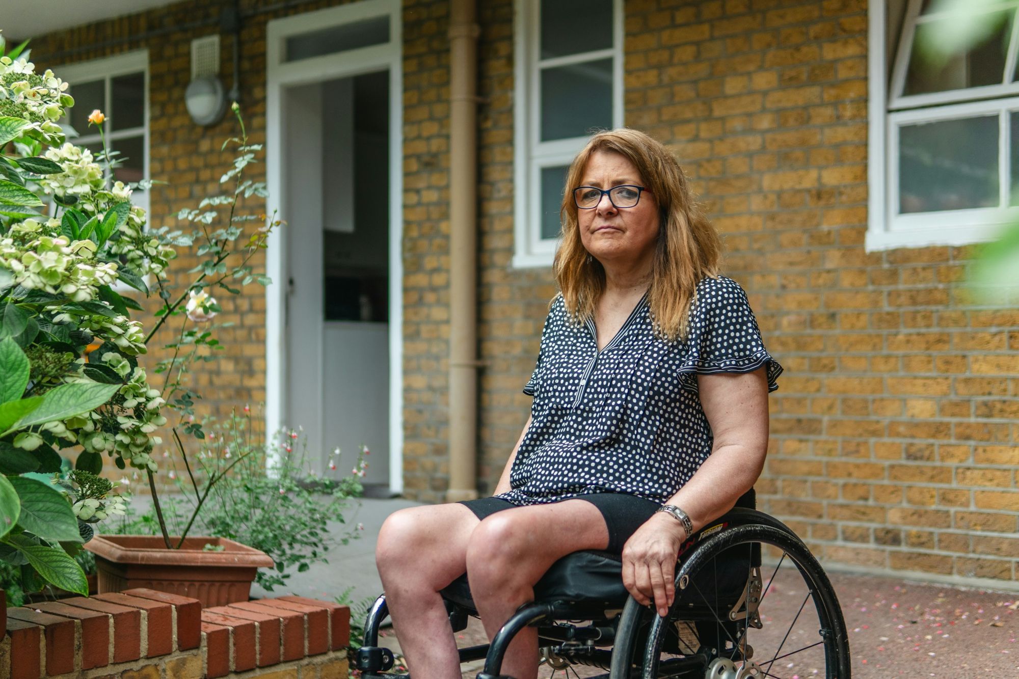 A woman in a wheelchair outside the front door of her home
