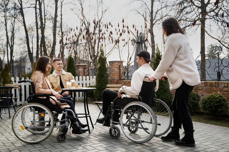 Friends, some using wheelchairs, chatting around a garden table