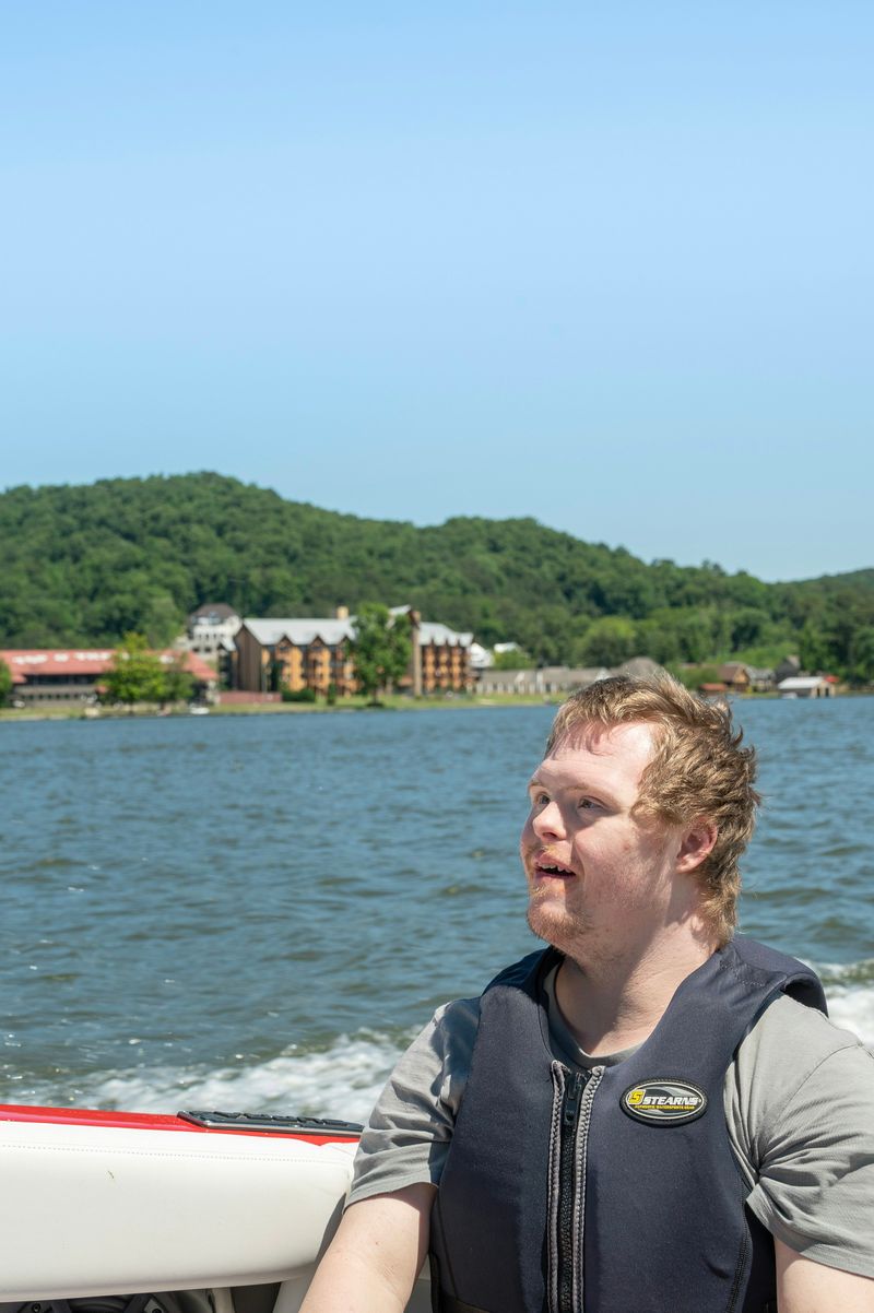 A smiling young man with Down’s syndrome by a lake