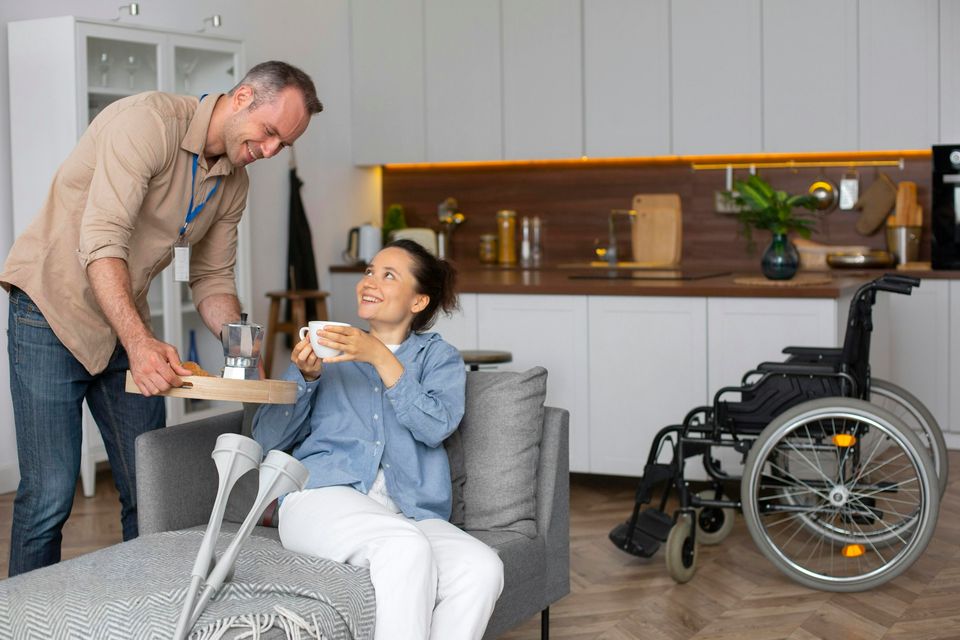 A support worker bringing coffee to a young woman in her living room