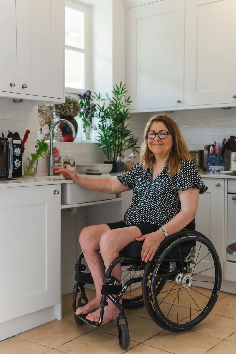 A woman in a wheelchair at the sink in her own kitchen